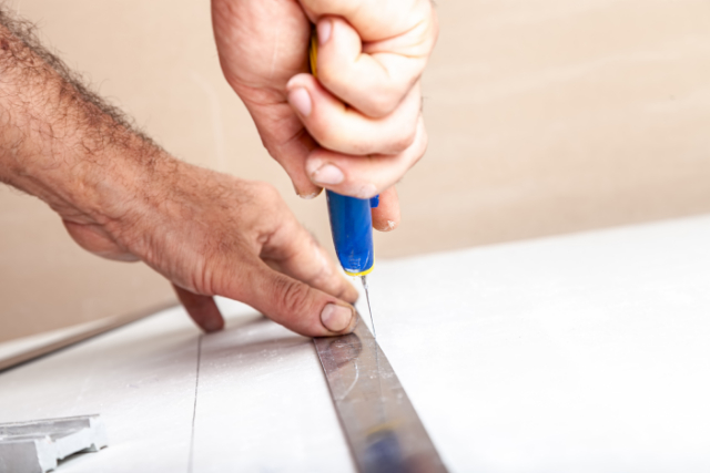 Drywall repair by worker and a ruler and knife