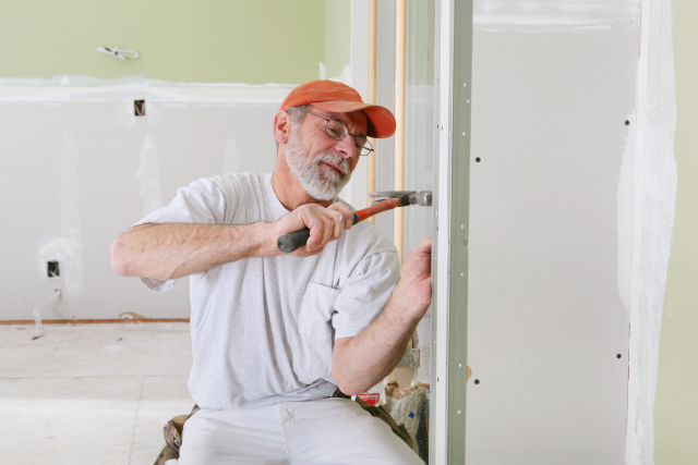 Drywall installation being done by worker with a hammer